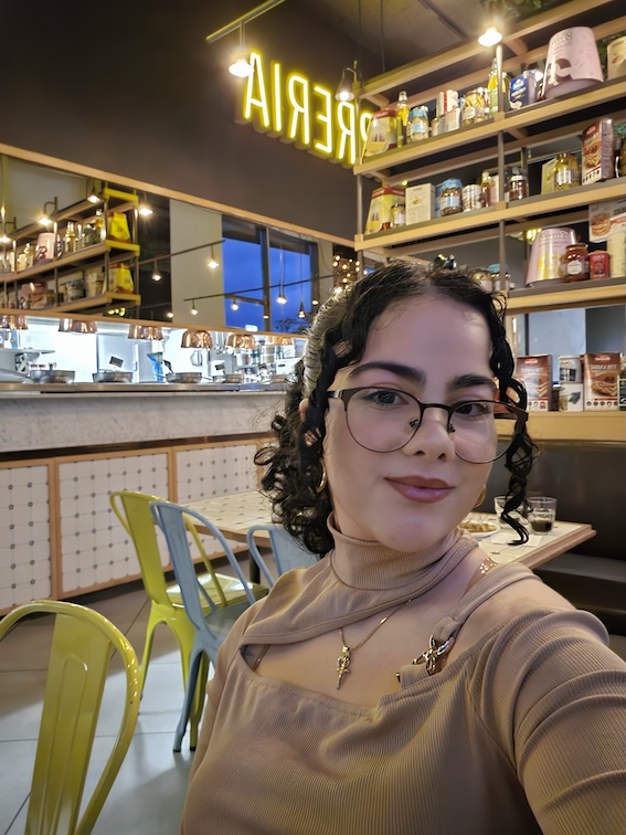 En kvinna med glasögon i kafémiljö.