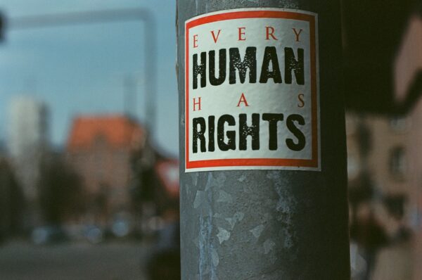 Närbild av en lyckstolpe med en klisterlapp med text. På lappen står det: Every human has rights