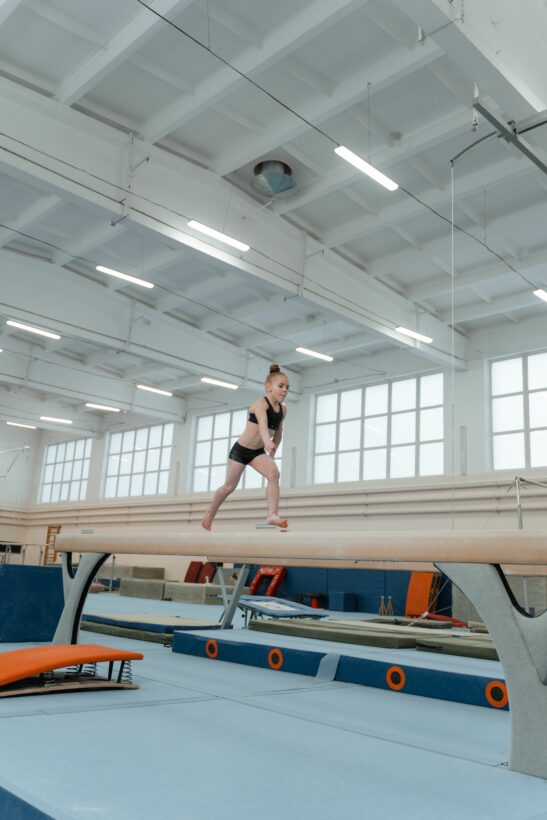 flicka på bom i färd med en gymnastikrörelse.