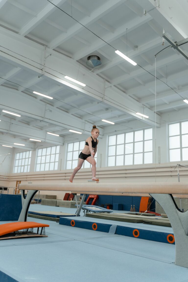 flicka på bom i färd med en gymnastikrörelse.
